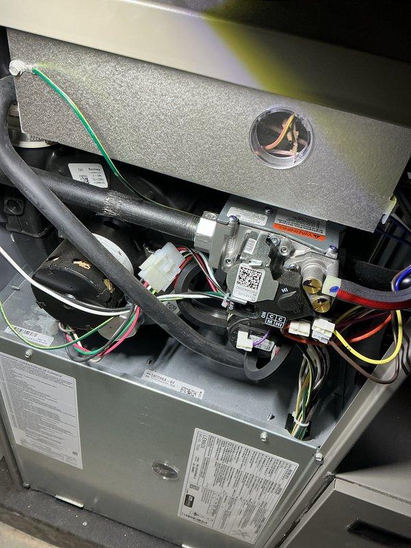 Completed comprehensive Air Care heating and cooling maintenance service on residential HVAC system. Performed full inspection of furnace unit with access panel removal, examining gas valve assembly, heat exchanger, and blower housing components. Verified proper operation of electronic gas valve controls and checked all electrical connections including multi-colored wire harnesses and safety circuits. Inspected gas line connections, rubber hoses, and flexible tubing for wear or deterioration. Confirmed all manufacturer specifications and regulatory compliance labels were present and legible. System components found to be clean, well-maintained, and operating within normal parameters.