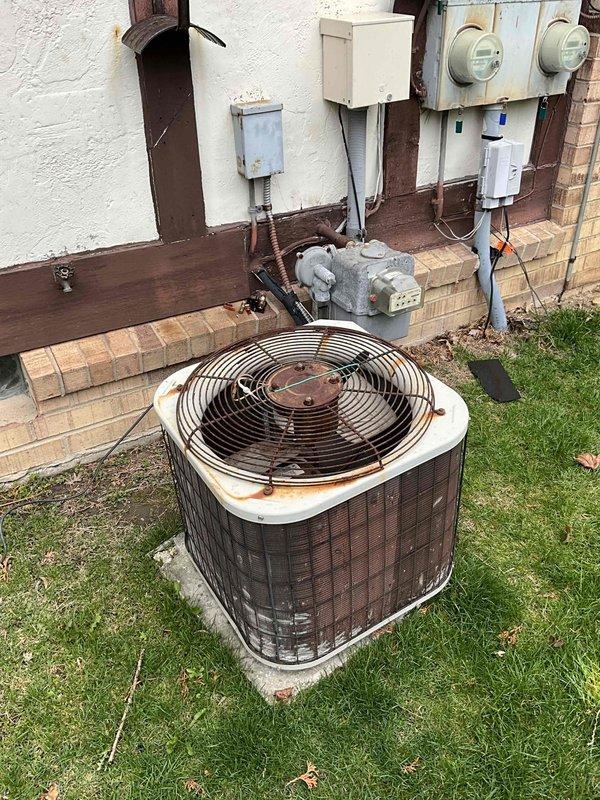 Provided estimate for complete air conditioning system replacement. Existing outdoor condenser unit from 1993 showed extensive rust staining, weathering, and age-related deterioration, resulting in non-operational cooling system. Assessed outdoor unit positioned on concrete pad, noted compromised cabinet integrity and failing components. Evaluated indoor furnace system in basement mechanical room, including existing Lennox furnace and ductwork configuration. Prepared comprehensive replacement proposal for new cooling equipment to restore residential comfort system functionality.