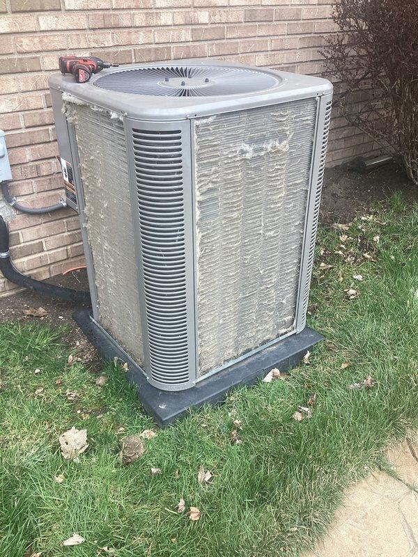 Completed annual cooling maintenance on residential air conditioning system. Contacted customer prior to arrival as requested. Performed comprehensive inspection of outdoor condenser unit, including examination of cabinet condition, coil fins, and fan assembly. Documented equipment condition through photographic records showing unit positioned on concrete pad against exterior brick wall with electrical disconnect and conduit properly installed. Condenser exhibited normal weathering and outdoor exposure with accumulated surface dirt and debris on metal panels and louvered vents. Verified unit accessibility and clearance around equipment for proper airflow and future service access.