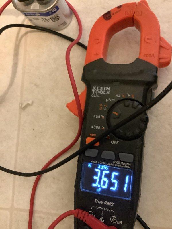 Performed routine Air Care Maintenance on cooling system. Inspected and documented return air filter condition showing normal dust accumulation through hexagonal grille openings. Tested system capacitor using clamp meter, recording 3.651 nF capacitance reading to verify component is operating within acceptable parameters for continued reliable operation.
