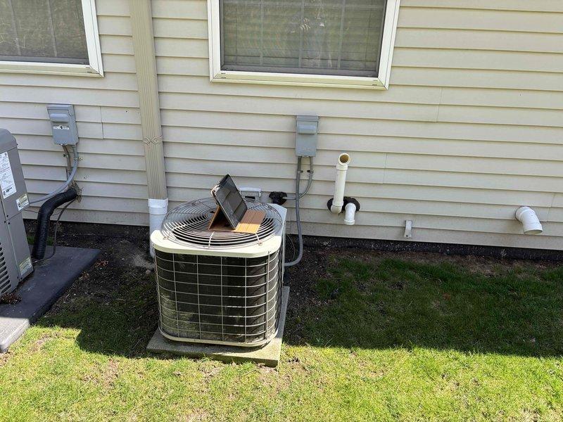 Conducted on-site assessment for furnace replacement estimate on 25-year-old Bryant heating system located in basement mechanical room. Inspected existing furnace installation, ductwork connections, and associated components including water heater proximity and available workspace. Documented current equipment condition showing aged furnace with standard vertical installation, proper ductwork routing, and existing PVC drain lines. Evaluated exterior air conditioning condenser unit on concrete pad to assess compatibility for potential system replacement options. Photographed mechanical room layout, equipment specifications, clearances, and utility connections to prepare comprehensive replacement quote. Confirmed basement access for equipment removal and new installation, noting concrete floor and adequate working space. Assessed electrical service, gas line connections, and existing vent configuration for replacement system requirements.