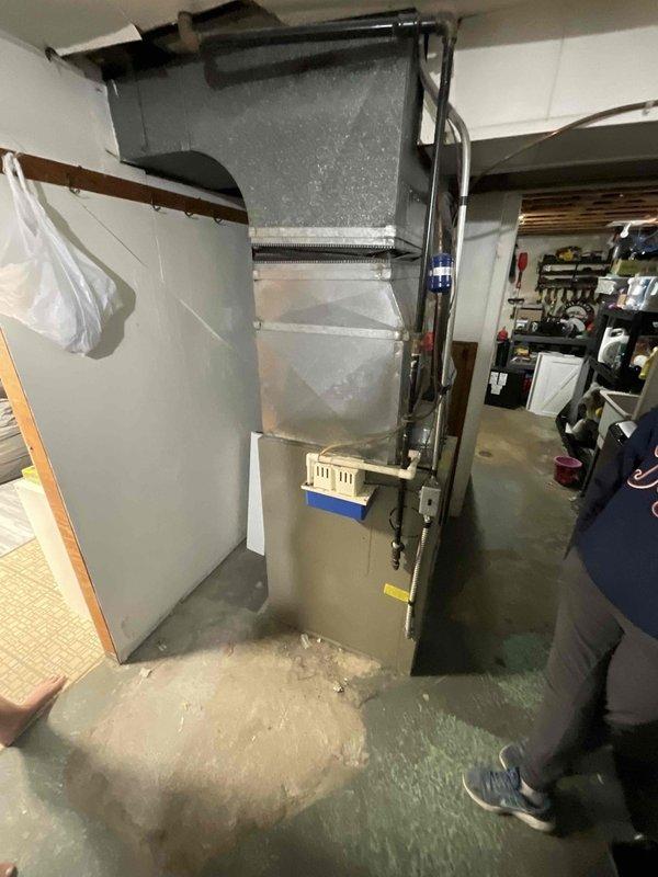 Conducted on-site assessment and provided replacement estimate for 27-year-old furnace and air conditioning system. Documented existing HVAC equipment condition, including basement-installed upright furnace with metal ductwork and plenum assembly, noting significant water accumulation on concrete floor surrounding unit base indicating potential condensate drain failure or leak. Photographed current system configuration and presented replacement options for complete heating and cooling system upgrade.