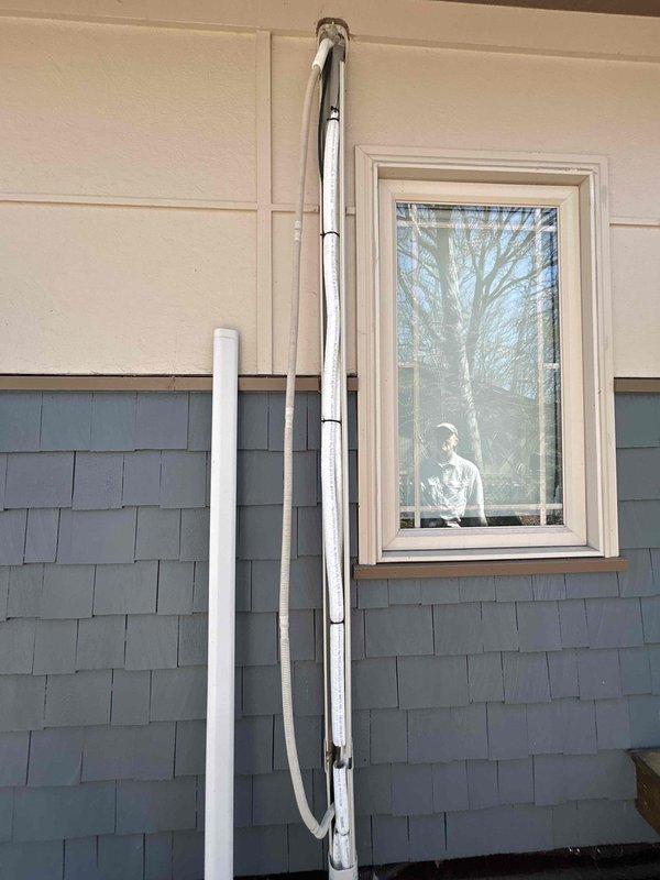 Responded to service call for Mitsubishi mini split system experiencing water leakage in bathroom installation. Upon arrival, inspected 23-year-old unit and confirmed active water leak from indoor air handler. Previous contractor had identified potential kinked drain line as source of issue. Performed thorough visual inspection of condensate drainage system, including primary drain line routing from air handler through exterior wall penetration. Examined refrigerant line set and condensate piping installation along exterior siding, noting multiple bends in metallic conduit system. Accessed ceiling-mounted air handler unit to assess internal drain pan condition and verify proper drainage flow. Corrected kinked section of condensate drain line that was restricting water flow and causing backup into the unit. Tested system operation and verified proper condensate drainage with no further leakage detected.