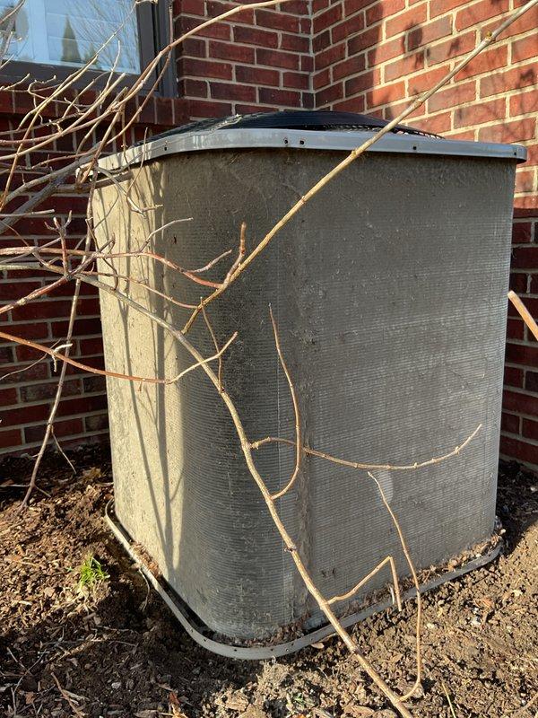 Completed annual HVAC maintenance on outdoor condenser unit. Cleared accumulated debris, bare branches, and vegetation from unit exterior and surrounding area. Replaced air filter as needed and documented pre-service condition showing significant dirt and grime buildup on metal casing and fins.