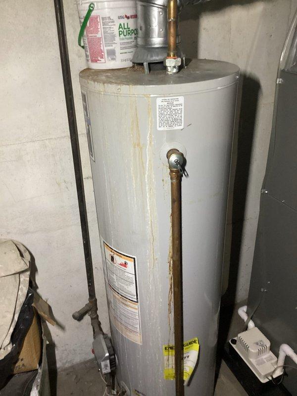 Responded to service call for leaking tanked water heater. Upon arrival, found residential gas-fired water heater with extensive rust staining and corrosion on tank exterior, indicating active leak from tank body. Inspected all plumbing connections, pressure relief valve, and supply lines to confirm leak source was compromised tank integrity rather than fitting failure. Documented unit condition with photographs showing deteriorated tank with rust streaks, corroded surfaces, and temporary bucket placed on top to catch condensation. Assessed copper supply piping and shutoff valve configuration. Advised customer that tank failure requires complete water heater replacement as tank leaks cannot be repaired. Provided recommendations for new unit installation.