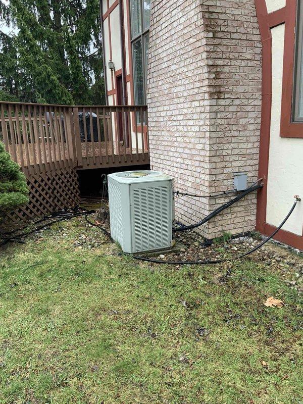 Completed site assessment for replacement estimate of 14-year-old furnace and air conditioning system in residential basement installation. Evaluated existing natural gas furnace and outdoor condensing unit positioned on exterior gravel pad adjacent to white brick foundation. Documented current system configuration including electrical service panel setup, conduit routing, and equipment accessibility for future BOGO replacement installation.