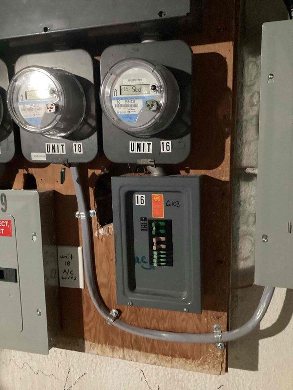 Completed electrical panel estimate for basement panel replacement serving Units 16 and 18. Assessed existing dual-meter installation with individual digital utility meters mounted on wooden backing board, gray electrical panel box with circuit breakers, and metallic conduit connections between components. Documented current configuration through photographs to provide accurate scope of work for panel replacement project.