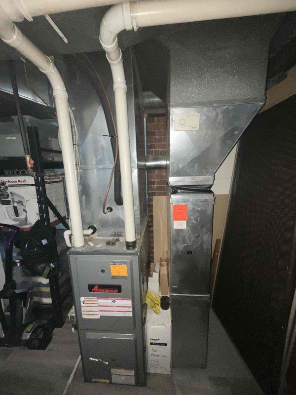 Conducted comprehensive assessment of existing 15-year-old HVAC system including furnace and air conditioning unit for replacement estimate. Documented current equipment configuration in basement mechanical room, noting gray metal furnace with PVC venting system and adjacent air handler unit. Evaluated system layout, existing ductwork connections, black flexible duct routing, and copper piping infrastructure. Photographed all equipment specifications, manufacturer labels, and mechanical components to prepare detailed replacement quote for complete furnace and AC installation.