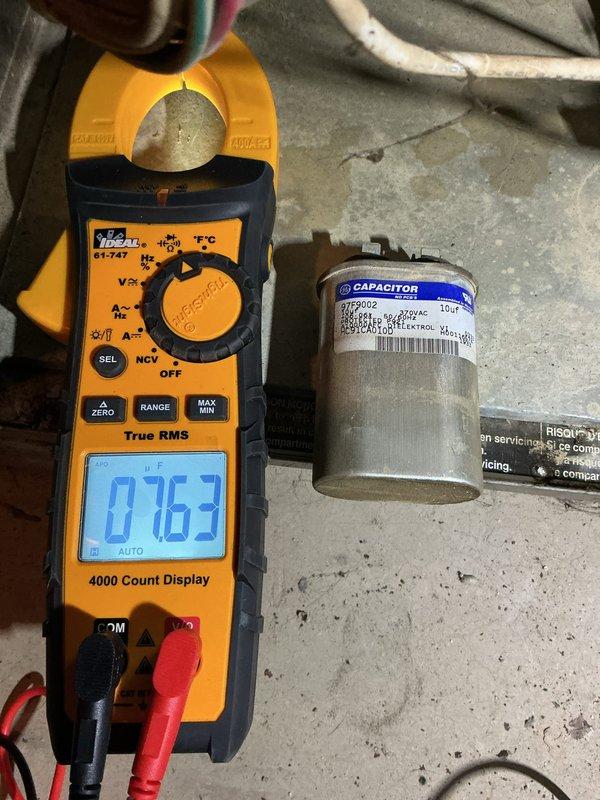 Responded to no heat call on 16-year-old forced air furnace that would run for one minute after reset button was pressed, then shut down. Diagnosed failed run capacitor using clamp meter, which showed capacitance reading of 0.067 microfarads, well below manufacturer specifications. Removed defective capacitor from blower assembly and replaced with new OEM-equivalent component. Tested system operation through multiple heating cycles to verify proper blower motor startup and continuous operation. System restored to full heating functionality.