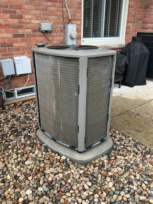 Completed scheduled ACM preventive maintenance on residential outdoor condensing unit. Performed comprehensive inspection of cylindrical unit including cleaning of bronze-colored mesh panels, verification of electrical connections at disconnect box, and assessment of refrigerant lines. Unit operational with all components functioning within normal parameters.