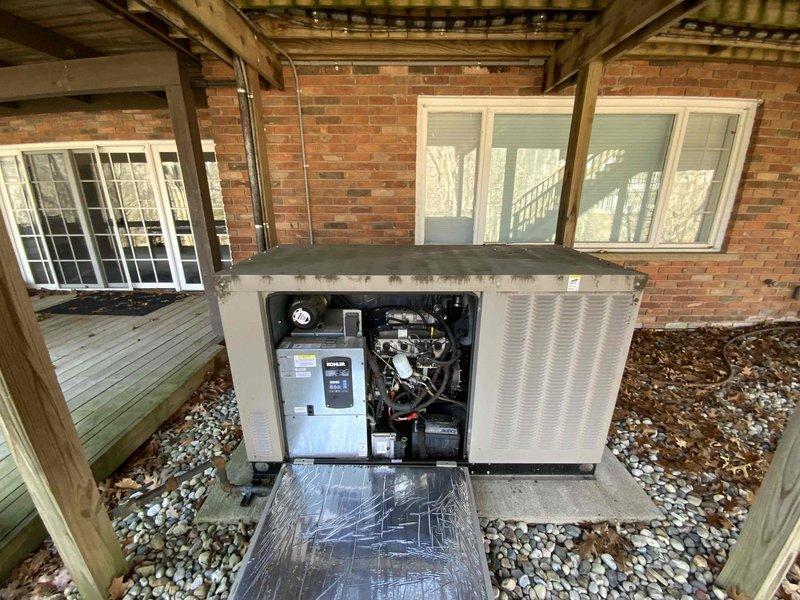Conducted site visit to outdoor HVAC packaged unit located beneath residential deck structure. Accessed internal compartment, photographed electrical control box, motor assembly, wiring connections, and mechanical components for documentation and assessment purposes. Unit positioned on concrete pad with proper drainage and weather protection from overhead deck covering.