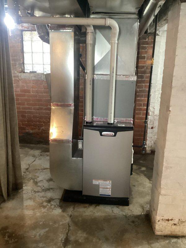 Successfully installed a 90,000 BTU high-efficiency furnace in residential basement location. Unit was positioned on base pad with proper clearances, connected to existing ductwork system using black flexible ducting, and white PVC venting installed for combustion air and exhaust. Electrical reconnection completed to power the new system, and all mechanical and electrical permits were obtained prior to installation.