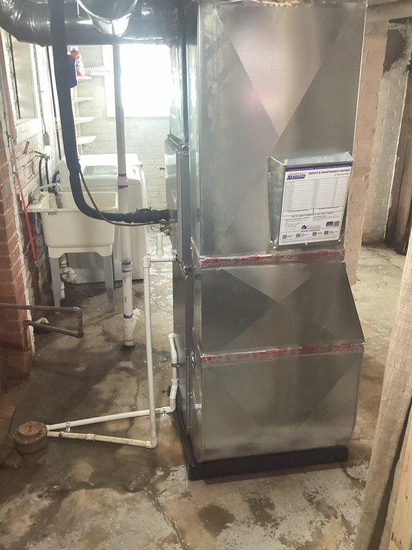 Successfully installed a 90,000 BTU high-efficiency furnace in residential basement location. Unit was positioned on base pad with proper clearances, connected to existing ductwork system using black flexible ducting, and white PVC venting installed for combustion air and exhaust. Electrical reconnection completed to power the new system, and all mechanical and electrical permits were obtained prior to installation.