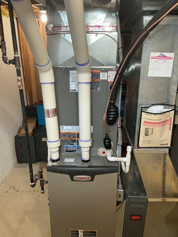 Completed full installation of 3-ton air conditioning system with evaporator coil in basement mechanical room. Unit positioned on left side with proper electrical reconnection and mechanical hookup to existing Lennox furnace system. All required mechanical, electrical, and air conditioning permits secured prior to installation. System includes proper condensate drainage with PVC piping, white intake/exhaust venting through ceiling, and integrated ductwork connections to air handler. Installation verified operational with all safety labels and manufacturer specifications properly displayed on equipment.