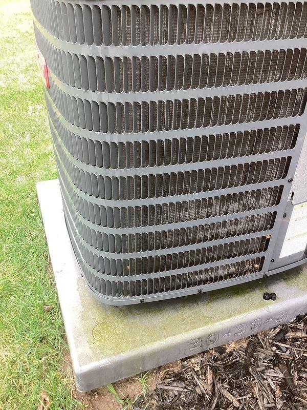 Completed annual maintenance on outdoor air conditioning condenser unit. Performed comprehensive inspection of heat exchanger coil fins, noting light to moderate dirt accumulation and discoloration on lower sections with minor debris caught in upper fin rows. Cleared organic debris including leaves and twigs from around unit base and concrete pad. Verified condenser positioning on concrete foundation and checked overall system condition. Unit fins showed normal weathering consistent with outdoor exposure, with uniform spacing maintained throughout coil assembly.