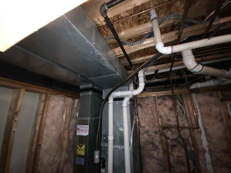 Conducted on-site assessment for complete HVAC system replacement in above-ground basement location. Existing 20-year-old natural gas furnace and air conditioning system were non-operational and required full replacement. Evaluated current equipment configuration including gas furnace unit, associated PVC condensate drainage system, refrigerant line sets, electrical connections, and ductwork installation within exposed basement utility area. Documented existing system layout with furnace positioned on concrete floor with wooden platform support structure, multiple PVC drain lines, copper refrigerant tubing, gas valve assembly, and integration with water heating equipment. Assessed installation environment including foundation walls, exposed ceiling joists, existing ductwork routing, and available space for new equipment placement. Provided comprehensive replacement estimate for new high-efficiency air conditioning and natural gas furnace system to restore climate control functionality.
