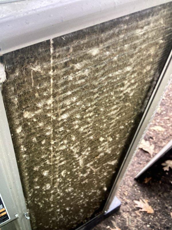 Completed recurring Air Care Heating and Cooling maintenance service on AHC system. Documented heavily soiled air filter with extensive dust and debris accumulation requiring replacement. Inspected condenser coil assembly showing significant contamination on heat exchanger fins with dirt buildup and mineral deposits affecting airflow efficiency. System components assessed and photographed for maintenance records.