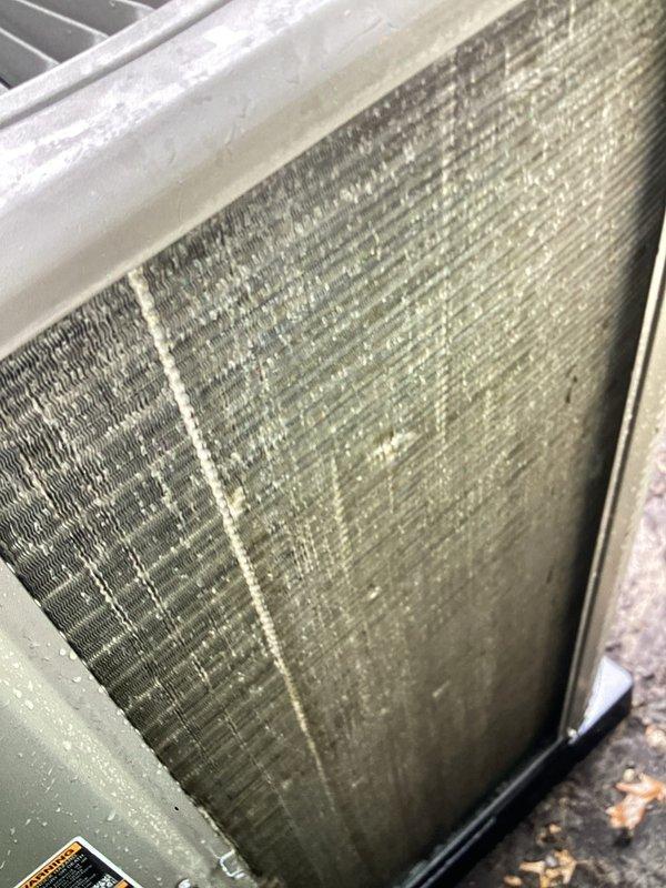 Completed recurring Air Care Heating and Cooling maintenance service on AHC system. Documented heavily soiled air filter with extensive dust and debris accumulation requiring replacement. Inspected condenser coil assembly showing significant contamination on heat exchanger fins with dirt buildup and mineral deposits affecting airflow efficiency. System components assessed and photographed for maintenance records.