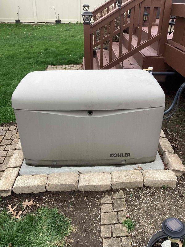 Completed comprehensive 5-year recurring maintenance service on a Kohler 14KW residential standby generator as part of ComfortGuard Package. Performed thorough inspection of generator unit positioned on concrete paver pad, verifying proper installation clearances and foundation stability. Conducted complete system diagnostics, checked all operational parameters, and confirmed unit functionality. Inspected exterior casing for weathering and minor dirt accumulation, noting overall good condition. Verified proper ventilation and clearance around unit. Documented equipment condition with photographic records showing generator installation and surrounding area.