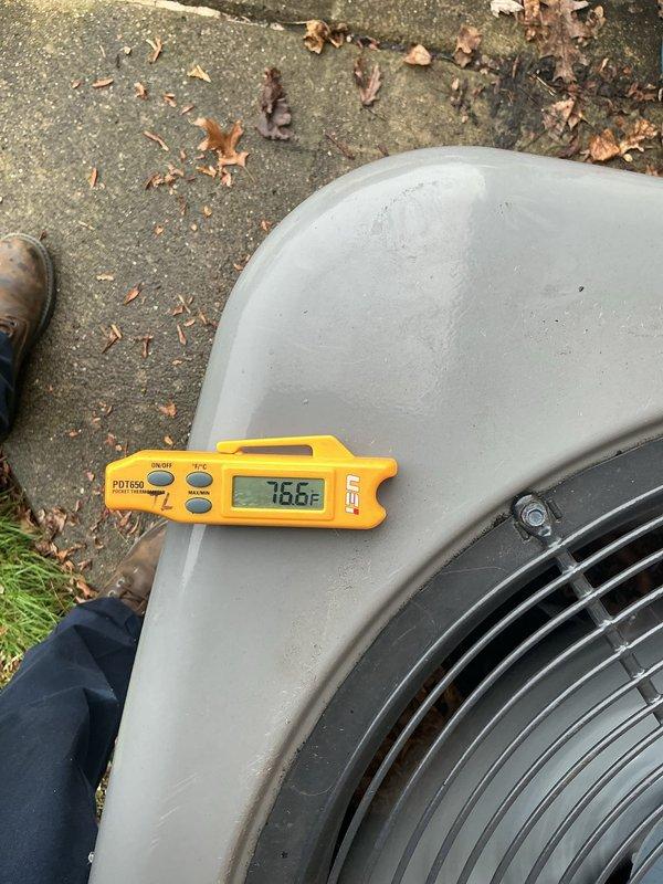 Completed annual cooling maintenance on residential outdoor condensing unit. Performed comprehensive system inspection, cleaned condenser coils, removed accumulated leaves and debris from base and mounting pad, verified refrigerant temperatures reading 76.6°F at unit surface, and confirmed proper operation of all components including fan motor and electrical connections.