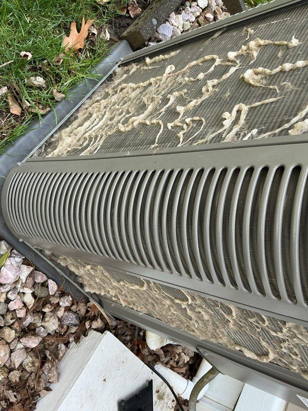 # HVAC Maintenance - ACM Completed

Performed annual cooling maintenance on outdoor condensing unit. Upon arrival, found significant accumulation of organic debris including seed fluff, cottonwood fibers, and plant matter covering the top mesh screen and louvers. Removed debris from condenser coil fins and top grille to restore proper airflow. Cleaned exterior surfaces and cleared leaves and organic material from around unit perimeter and base. Inspected condensing unit components for proper operation. Verified drainage connections and confirmed unit positioned securely on concrete pad. System operational following maintenance service.