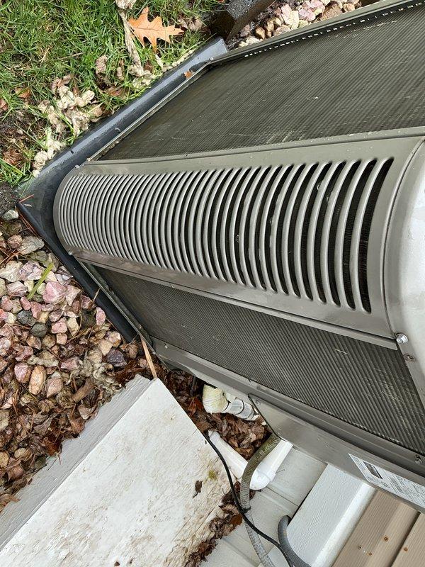 # HVAC Maintenance - ACM Completed

Performed annual cooling maintenance on outdoor condensing unit. Upon arrival, found significant accumulation of organic debris including seed fluff, cottonwood fibers, and plant matter covering the top mesh screen and louvers. Removed debris from condenser coil fins and top grille to restore proper airflow. Cleaned exterior surfaces and cleared leaves and organic material from around unit perimeter and base. Inspected condensing unit components for proper operation. Verified drainage connections and confirmed unit positioned securely on concrete pad. System operational following maintenance service.