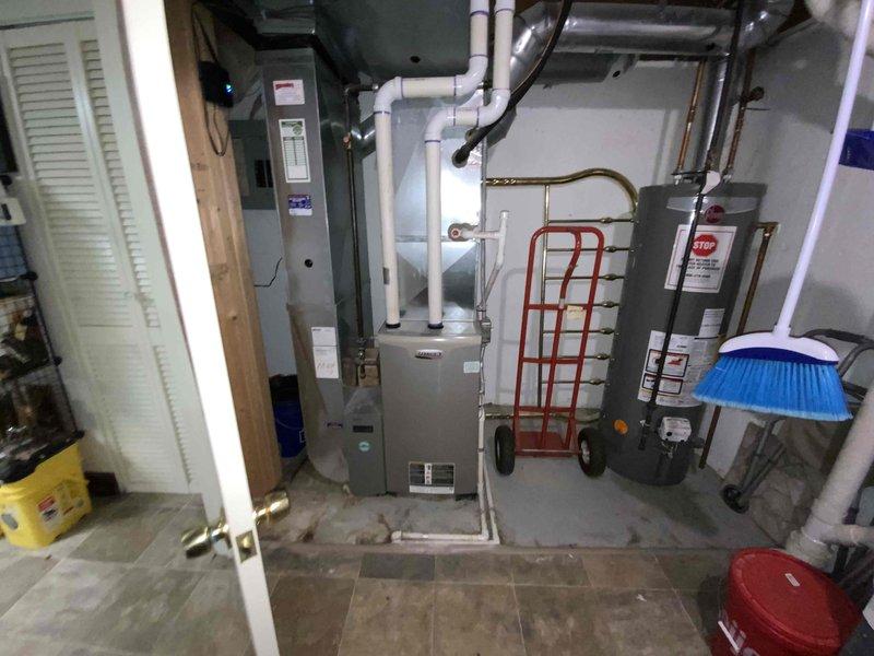 Conducted site evaluation for replacement of 30-year-old air conditioning system in residential basement mechanical room. Assessed existing HVAC equipment configuration, including furnace with PVC exhaust venting, water heater, and associated copper piping and ductwork. Documented current system layout and utility connections to prepare comprehensive replacement estimate for complete air conditioning unit installation.