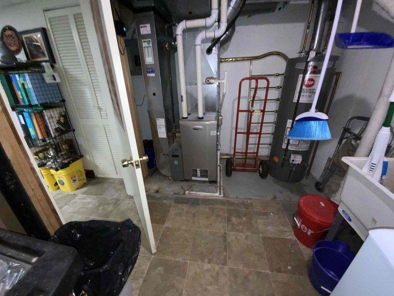 Conducted site evaluation for replacement of 30-year-old air conditioning system in residential basement mechanical room. Assessed existing HVAC equipment configuration, including furnace with PVC exhaust venting, water heater, and associated copper piping and ductwork. Documented current system layout and utility connections to prepare comprehensive replacement estimate for complete air conditioning unit installation.