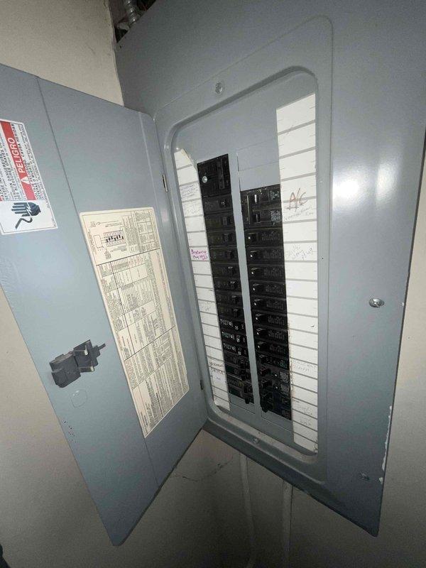 Conducted site assessment for 3-zone ductless mini-split heat pump installation to replace existing steam furnace heating system and window air conditioning units. Evaluated upper-floor room measuring 10x16 feet with sloped ceiling at 95 inches, documented window dimensions and optimal indoor unit placement locations. Inspected existing electrical panel capacity and breaker configuration to determine compatibility with new multi-zone heat pump system requirements and verified adequate amperage availability for installation.