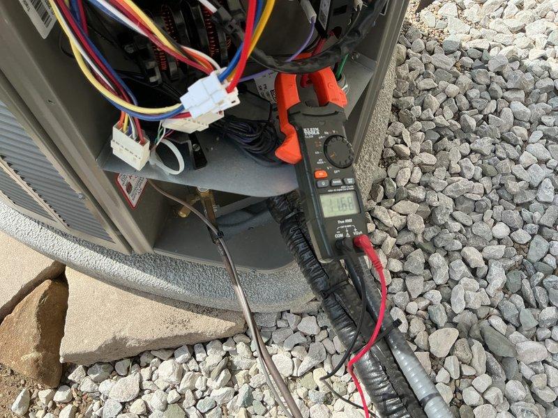 Completed scheduled air conditioning maintenance on residential cooling system. Performed electrical diagnostics using digital multimeter, recording voltage reading of 6.12V at control circuit. Measured operating amperage of unit at 16.6 amps using clamp meter at compressor circuit. Inspected internal electrical components, wiring connections, and control board within outdoor condensing unit. Verified proper wire terminations and cable management. System operational upon completion of maintenance inspection.