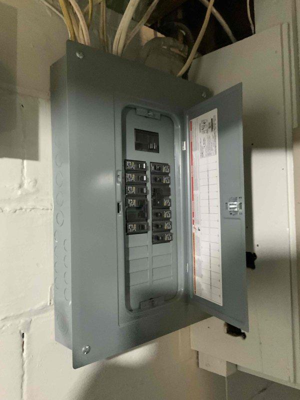 Conducted site evaluation for new air conditioning system installation at residential single family home with no existing AC unit. Assessed electrical infrastructure in basement utility area, documenting existing electrical panels and circuit breaker capacity to determine compatibility and requirements for new AC system installation. Photographed electrical service panels, conduit routing, and available space for future equipment connections to support accurate equipment sizing and installation planning.