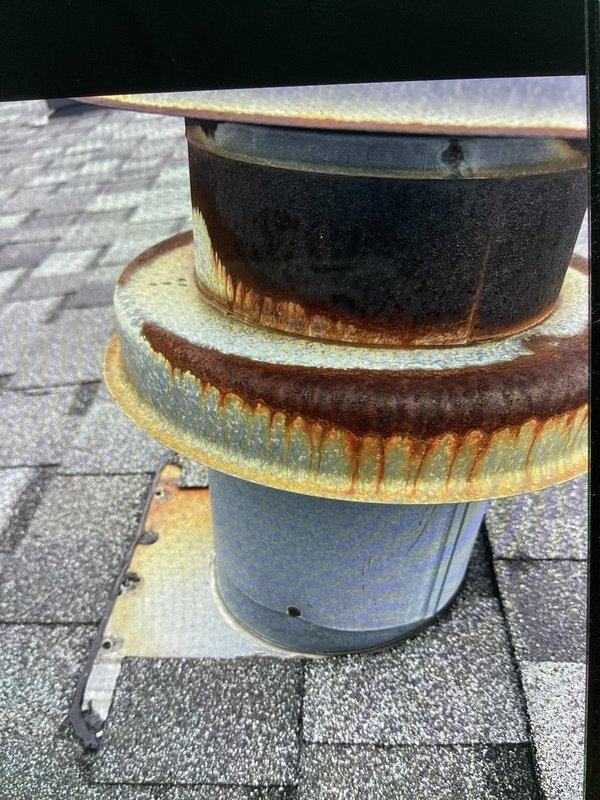 Responded to call for water leaking from venting onto 3-year-old furnace in mobile home. Upon inspection, discovered severely corroded roof vent termination cap with heavy rust deterioration allowing water infiltration through the flue system. Documented contamination and water damage on furnace cabinet and surrounding components caused by compromised vent assembly. Advised replacement of corroded vent cap and inspection of flue pipe integrity to prevent further water intrusion and potential safety hazards.