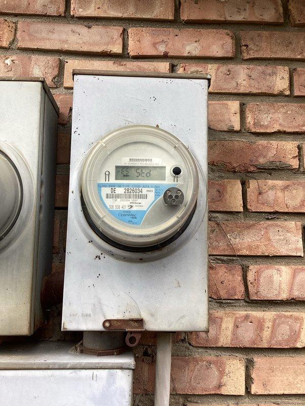 Completed estimate for whole-home surge protector installation at a 1972 condominium. Inspected existing electrical service consisting of multiple digital electric meters mounted on exterior brick wall with weathered metal enclosures. Documented current metering configuration showing three OpenWay digital meters serving multiple units with various conduits and wiring connections. Assessed panel accessibility and existing grounding system, noting exposed grounding conductors present at installation. Photographed meter bank arrangement and service entrance equipment to determine optimal surge protection device placement and compatibility with existing infrastructure. Provided recommendations for Type 2 surge protective device installation based on observed electrical service configuration and building age.
