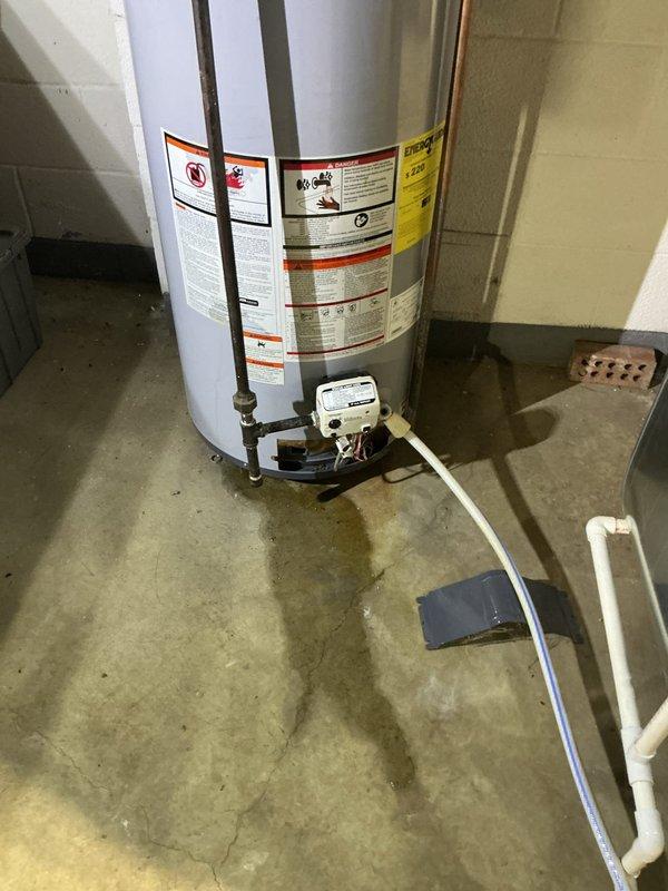 Performed diagnostic inspection on residential tanked water heater experiencing moisture accumulation at base of unit. Upon arrival, observed significant water pooling on concrete floor surrounding water heater, indicating active leak or condensation issue. Conducted thorough visual examination of tank exterior, plumbing connections, temperature and pressure relief valve, and drain valve assembly. Inspected copper supply lines and shutoff valves at top of unit for signs of corrosion or fitting failures. Evaluated control valve assembly and bottom drain connection for potential leak sources. Documented existing conditions with photographic evidence showing water damage patterns on floor and overall system configuration. Advised customer that no warranty coverage applies to this service call for parts or labor. Customer declined further repairs at this time following diagnostic assessment.