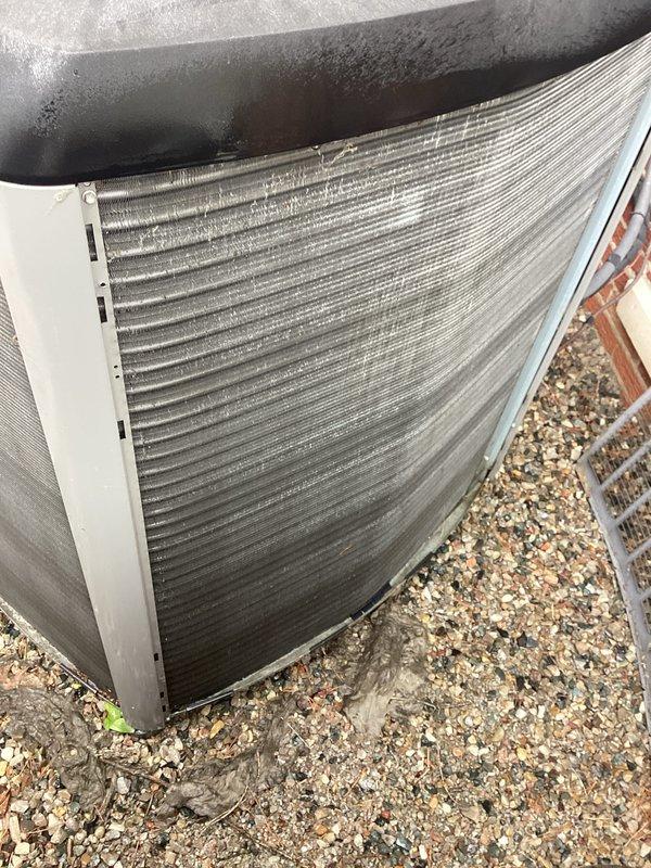 # HVAC System Annual Maintenance Completed

Performed comprehensive annual maintenance on residential HVAC system including furnace tune-up and outdoor heat pump unit inspection. Conducted thorough visual assessment of outdoor condenser unit positioned on gravel pad, noting accumulated dirt and debris on aluminum condenser coil fins. Documented unit condition through photographic records showing weathered exterior housing with moisture condensation on top panel and visible dirt accumulation between horizontal fins.

Inspected heat pump unit's cylindrical metal housing, noting weathered black exterior paint and protective fan grille covering. Observed foam insulation material along top section joint. Examined horizontal finned condenser coils displaying dirt accumulation, streaking, and grime buildup from environmental exposure. Unit positioned on mixed gravel base adjacent to brick wall structure.

Completed standard furnace tune-up procedures on brand new equipment (0 years old) as pa