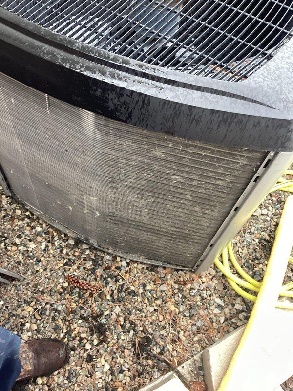 # HVAC System Annual Maintenance Completed

Performed comprehensive annual maintenance on residential HVAC system including furnace tune-up and outdoor heat pump unit inspection. Conducted thorough visual assessment of outdoor condenser unit positioned on gravel pad, noting accumulated dirt and debris on aluminum condenser coil fins. Documented unit condition through photographic records showing weathered exterior housing with moisture condensation on top panel and visible dirt accumulation between horizontal fins.

Inspected heat pump unit's cylindrical metal housing, noting weathered black exterior paint and protective fan grille covering. Observed foam insulation material along top section joint. Examined horizontal finned condenser coils displaying dirt accumulation, streaking, and grime buildup from environmental exposure. Unit positioned on mixed gravel base adjacent to brick wall structure.

Completed standard furnace tune-up procedures on brand new equipment (0 years old) as pa