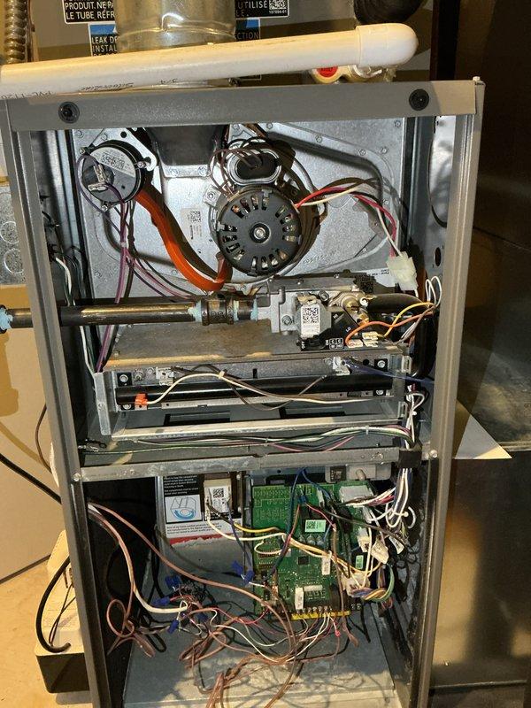 Completed annual furnace maintenance and tune-up on residential heating system. Performed comprehensive inspection of blower motor assembly, capacitor, gas valve connections, and main control board. Verified all electrical connections, wire harnesses, and safety controls are functioning properly. Documented equipment condition with interior cabinet photos showing motor assembly, combustion chamber, and control components in good operational status.