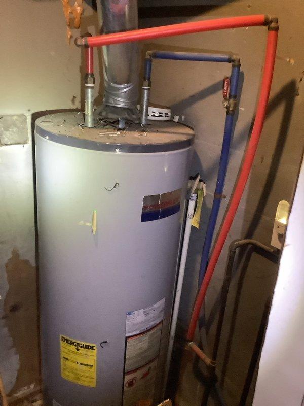 Responded to service call for air conditioning unit producing loud noise during operation and hot water heater failing to heat properly. Both units located in interior closet. Air conditioning system is less than one month old and covered under parts and labor warranty. Performed diagnostic inspection of AC unit to identify source of operational noise. Conducted assessment of hot water heater to determine cause of heating failure. Documented equipment condition and installation configuration with photographic evidence showing water heater with standard plumbing connections, color-coded supply lines, flue pipe, and manufacturer labeling intact.