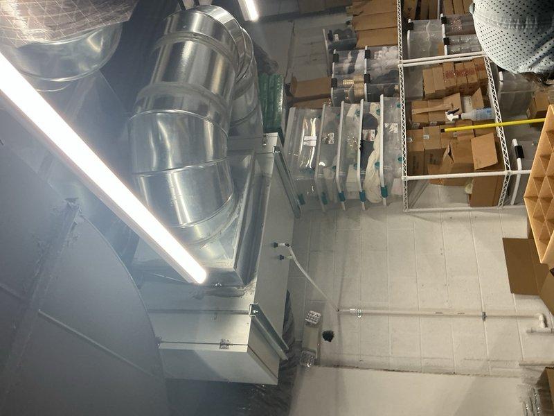 Arrived on-site during scheduled window for inspection of recently completed commercial HVAC installation. Documented two large-capacity air handling units with associated ductwork, electrical connections, and control components in warehouse mechanical space. Installation inspection confirmed proper equipment placement, secure duct connections, appropriate electrical terminations, and compliance with commercial building codes for final approval.