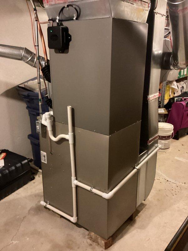 Completed installation of 3.5-ton air conditioning system with matching evaporator coil in residential basement location. Unit positioned on right-side configuration with copper refrigerant lines professionally routed and secured, connected to existing furnace system with proper ductwork integration. All mechanical and electrical permits obtained, condensate drainage system installed with PVC piping, and system reconnected and tested for proper operation.