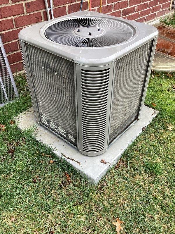 Completed annual cooling maintenance on residential split system air conditioning unit. Performed comprehensive inspection of outdoor condenser unit, noting heavy exterior soil and grime accumulation on cabinet panels requiring cleaning. Removed fan grille to access internal components, inspected condenser coils through protective mesh panels, verified refrigerant line connections at wall penetration, checked mounting and pad stability, and documented equipment condition. Unit operational with all safety features intact upon completion of preventive maintenance service.