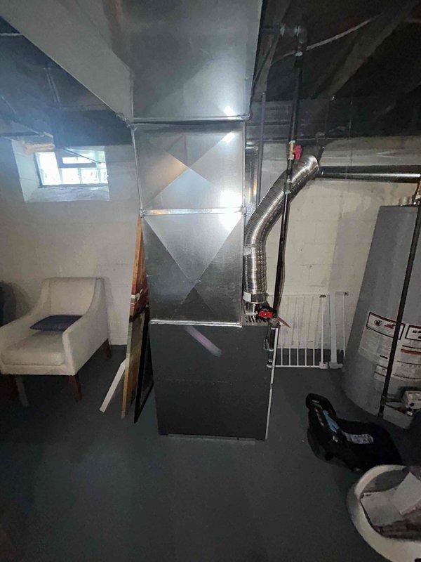 Conducted on-site evaluation for HVAC equipment replacement estimate in residential property. Assessed existing furnace installation located in basement utility area with current ductwork configuration including metallic flex ducting and sheet metal plenum system. Documented equipment layout, ductwork connections, and spatial requirements for potential air conditioning system installation and possible furnace replacement. Photographed existing HVAC infrastructure to support equipment sizing recommendations and installation planning.