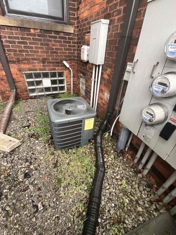 Completed full HVAC system estimate for outdoor air conditioning installation at commercial brick building location. Documentation included exterior condenser unit positioning on gravel pad with proper clearances, electrical metering infrastructure with three-meter assembly, dedicated disconnect box installation, and conduit routing along exterior wall. Interior electrical panel assessment showed dual-column breaker configuration with multiple feed cables entering from above, supporting system power requirements for complete HVAC installation.