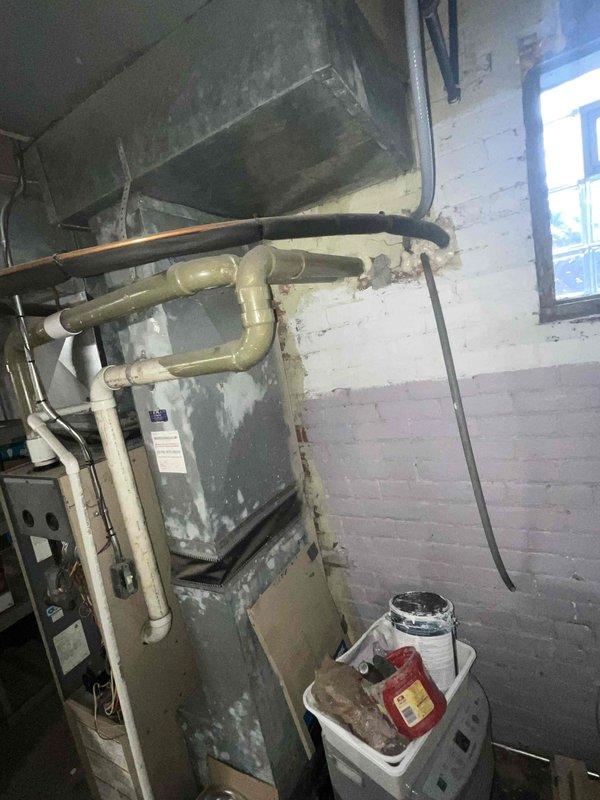 Completed comprehensive HVAC system evaluation for full system replacement estimate in basement utility area. Documented existing aging furnace unit showing significant wear, paint deterioration, and dust accumulation, along with connected ductwork and associated mechanical components. Photographed current system configuration including furnace with exposed burner assembly, blower motor, wiring connections, and galvanized metal ductwork to provide detailed assessment for complete system replacement proposal.