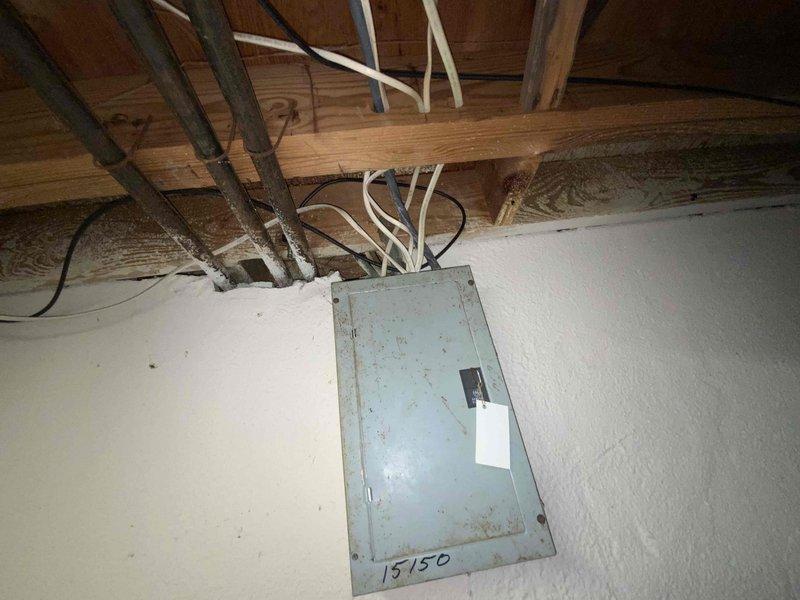 Performed full system estimate for 32-year-old Bryant R22 HVAC system experiencing active water leakage from deteriorated evaporator coil into blower cabinet due to rust perforation. Assessed non-repairable coil damage caused by age and obsolete refrigerant type, documented aging furnace of same vintage, and photographed existing electrical panel showing significant corrosion and utility room equipment layout. Provided replacement options for complete air conditioning system and furnace to prevent further equipment damage and ensure reliable operation.