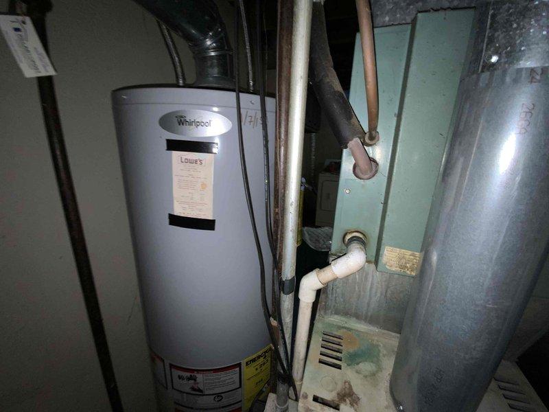 Performed full system estimate for 32-year-old Bryant R22 HVAC system experiencing active water leakage from deteriorated evaporator coil into blower cabinet due to rust perforation. Assessed non-repairable coil damage caused by age and obsolete refrigerant type, documented aging furnace of same vintage, and photographed existing electrical panel showing significant corrosion and utility room equipment layout. Provided replacement options for complete air conditioning system and furnace to prevent further equipment damage and ensure reliable operation.