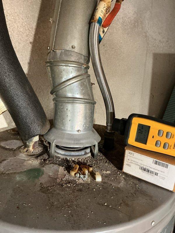 Completed annual HVAC maintenance inspection on water heater system. Performed diagnostic testing using digital meter to verify proper combustion and system operation, inspected flue pipe and venting components for proper draft and clearances, and examined all connections including gas flex line and associated fittings. Documented current condition of unit showing normal wear and debris accumulation at base, confirmed all safety controls functioning within specifications.