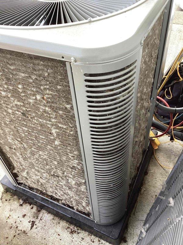 Responded to no cooling complaint on residential Trane system less than 2 years old. Upon arrival, found both furnace and AC unresponsive despite thermostat clicking when adjusted. Inspected outdoor condenser unit and documented condition showing significant dirt accumulation on coils and louvers, which can restrict airflow and reduce system efficiency. Photographed equipment for service records. System requires further diagnostic testing to determine root cause of complete system failure, as homeowner had already verified flood detector switch was not tripped.