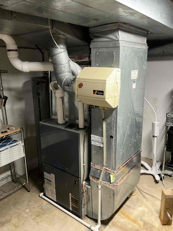 Completed comprehensive estimate for replacement of aging HVAC system including 17-year-old gas furnace and 10-year-old air conditioning unit located in basement utility area. Performed thorough assessment of existing equipment configuration, including galvanized steel furnace cabinet, air handler with humidification component, metal plenum assembly, and ductwork connections. Documented current system specifications, photographed existing installation showing PVC condensate drainage, flexible duct connections, and equipment placement on concrete floor for replacement planning purposes.