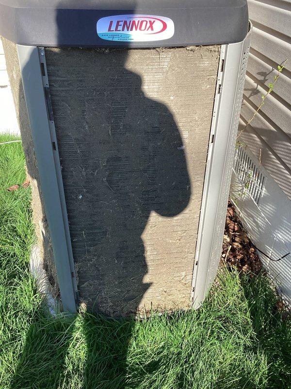 Responded to a no-cool complaint on a 2-year-old Lennox central air conditioning system. Upon inspection, discovered the outdoor unit's filter and front panel were heavily contaminated with dirt, dust, and debris buildup, severely restricting airflow to the condenser coil. Removed and cleaned the excessively soiled filter, which was clogged with gray-tan dust accumulation that had significantly impaired system performance and cooling capacity. The restricted airflow condition was causing inadequate heat rejection at the condenser, resulting in reduced cooling output to the living space. System restored to proper operation following cleaning.